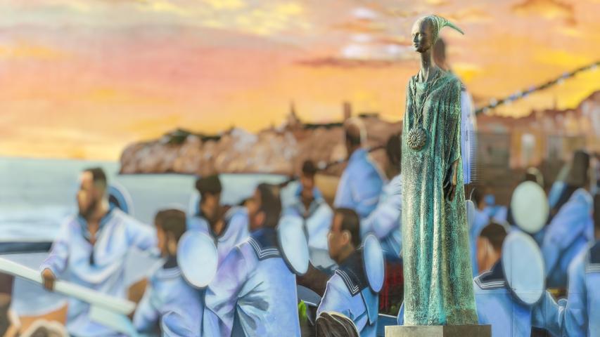 Imagen de Enero del Calendario 2026 (Manuel Rueda) con una instantánea de la estatua de Noctiluca con el fondo del mural de la procesión de la Virgen del Carmen